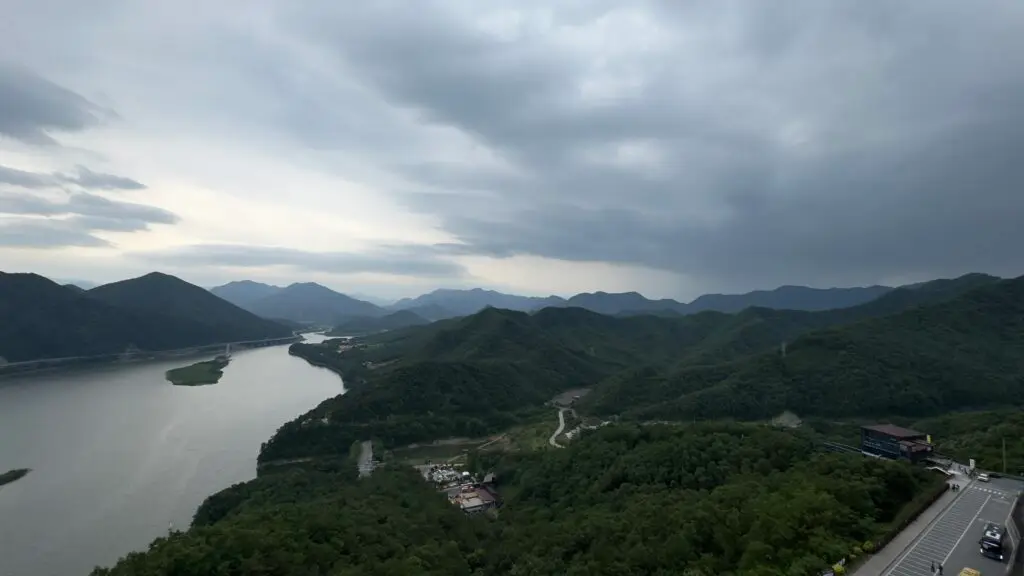 Scenic landscape view from the observation deck of 만천하스카이워크 in Danyang, South Korea, featuring winding river, forested mountains, and expansive sky.